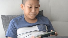 Young Asian boy playing game on smartphone at home
