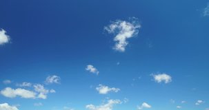 Time lapse video of white cumulus clouds running across blue sky