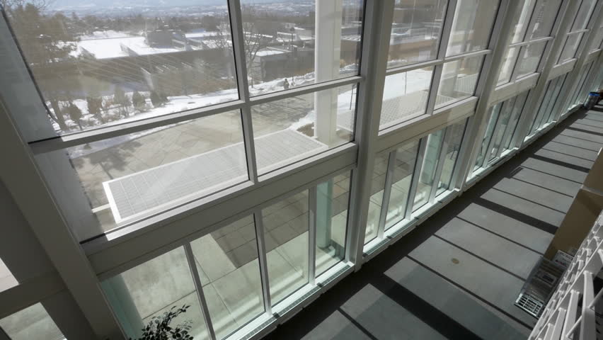 Two unidentifiable people walk past the large windows in Dwire Hall at University of Colorado Colorado Springs, Colorado.