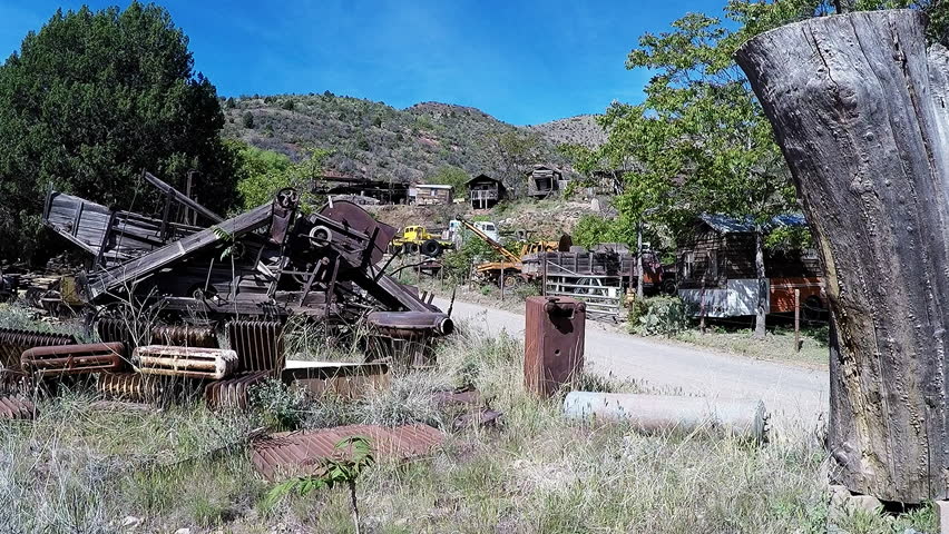 JEROME, AZ/USA: May 4, 2017- Shot of the Gold King Mine Ghost Town parking entrance in Jerome Arizona. Clip reveals view of tattered and weathered old relics rusting along dirt roadway.