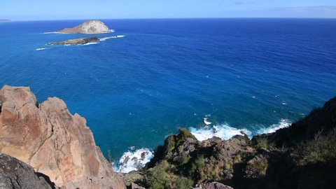 Steep rugged slope of Makapu'u Point with scenic view of Rabbit Island and deep blue Pacific Ocean on eastern coast of Oahu, Hawaii