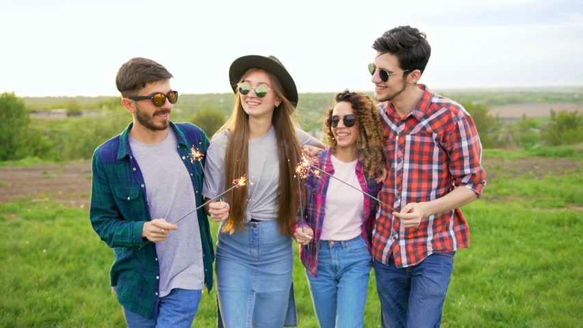 Group of four happy smiling friends walks with sparklers at slow motion. Summer leisure concept. Two women and two men Royalty-Free Stock Footage #27073792
