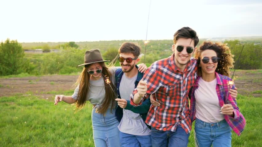 Happy stylish hipsters are running at the meadow, holding sparklers. Summer lifestyle concept Royalty-Free Stock Footage #27073798