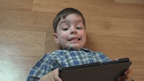 Little boy 4 years old brunette in a blue checkered shirt playing on a tablet 4k video resolution