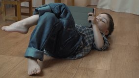 Little boy 4 years old brunette in a blue checkered shirt playing on a tablet 4k video resolution