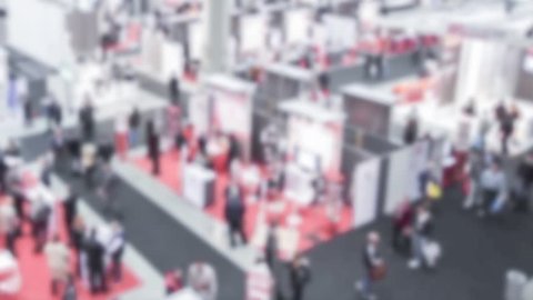 People visit a trade show, panoramic view. Background with an intentional blur effect applied. Time lapse.