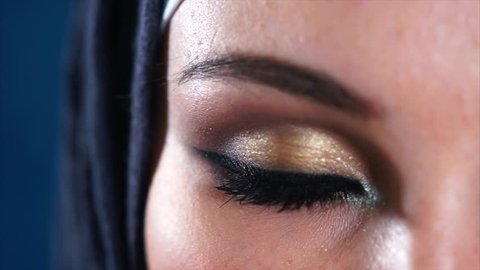 Extreme close-up of a young Middle Eastern Muslim woman in black hijab opening dark brown eyes and looking to the camera