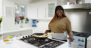 4K Cheerful woman cooking in modern domestic kitchen, doing piece to camera for TV show or internet channel