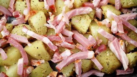 Peeled potatoes with spices, bacon meat and onion slices ready to be roasted close up. Food background. Dolly shot