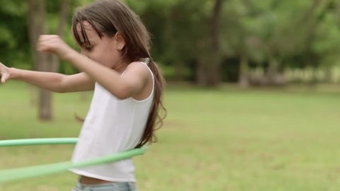 Children and toys, young girl having fun and playing with hula-hoop outdoors. Slow motion