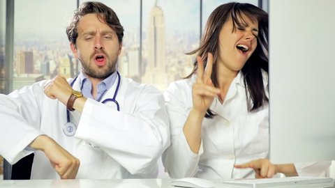 Man and woman doctor dancing and laughing like crazy in office in city