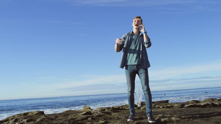 Young man is making a phone call on a beach
