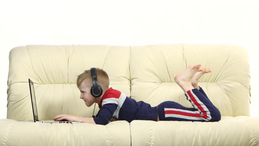 Teen playing online games on laptop in headphones on couch