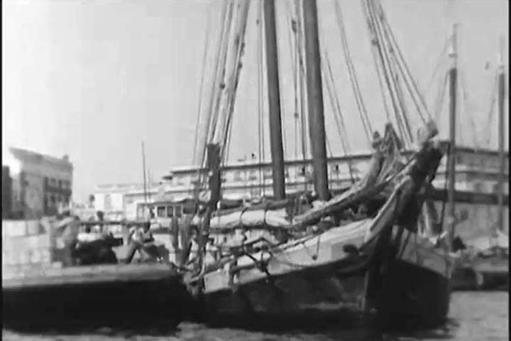 1920s: On the waterfront, barrels of seized rum are rolled along by dockworkers, in 1924.