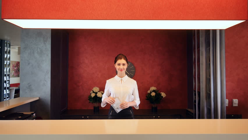 Receptionist greeting hotel guest, giving room key. 4K.