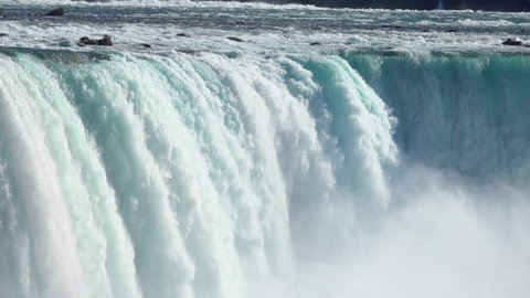CLOSE UP Powerful raging whitewater waterfall falling forcefully over a rocky edge. Crystal clear glacier water stream dropping over the steep vertical cliff. Misty majestic Niagara Falls river rapids