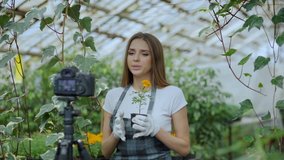 Young smiling blogger woman florist in apron talking and recording video blog for her online vlog about gardening