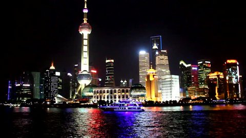 Shanghai bright skyline at night and boat with neon lights sailing by on the river.