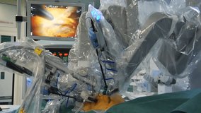 Robot performs heart surgery. Monitor shows procedure in background. 