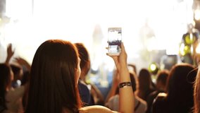 girl in the crowd shoots video on smart phone.girl standing in the middle of the concert crowd and holding mobile phone in her hands. 