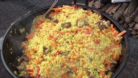 Pilaf is cooked on the grill in a large cauldron. Full HD 1920x1080 Video Clip