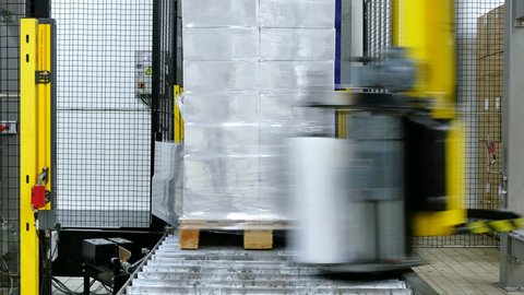 Boxes on a pallet wrapping with a foil by a heavy duty machine