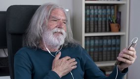 Old man sitting in chair listening to music with earphones, beating the time