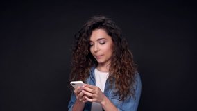 Happy Curly Woman using smartphone over black background