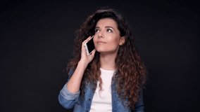 Happy Pretty Curly Woman talking by her smartphone over black background