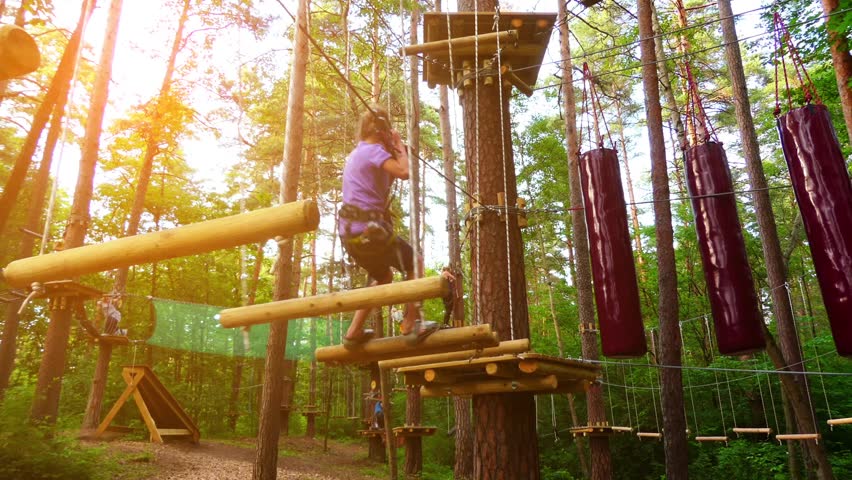 Small girl in adventure park. Adventure park is place which can contain wide variety of elements, such as rope climbing exercises, obstacle courses and zip-lines. They intended for recreation.