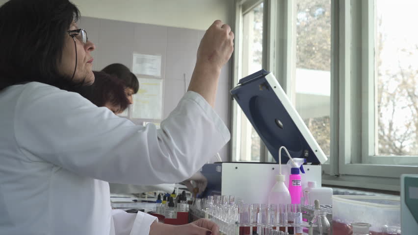 A team of female laboratory technicians and doctors specialist sit for the table with equipment and analyze blood samples in test tubes, dolly shot, face close up, room interior | Shutterstock HD Video #27143611