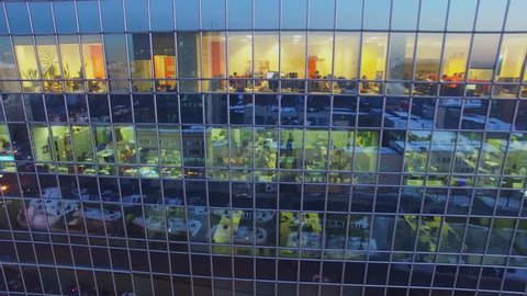 MOSCOW - FEB 16, 2017: People work in offices behind windows with reflection of city at winter evening. Aerial view