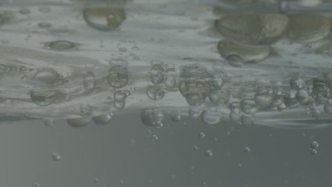 Water Bubbles Underneath the Surface - Shot from just underneath the surface of a grey body of water, showing bubbles and waves