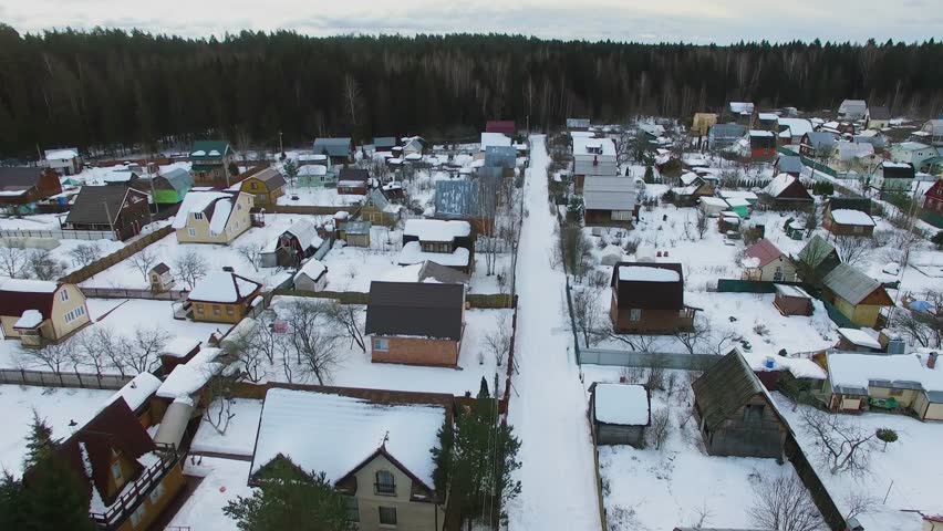 Snow covered country houses near forest at winter day. Aerial view