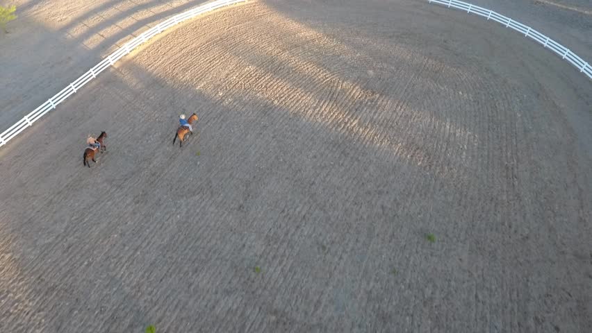 Aerial shot of 2 horseback riders in an arena