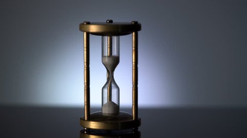 Time Lapse of Sand Flowing Through vintage metal hourglass on grey background.