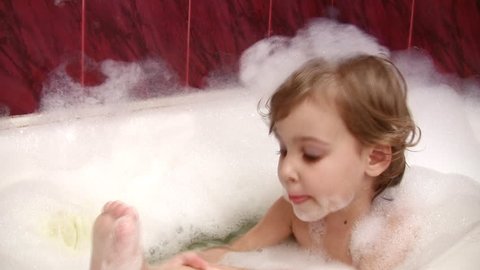 little girl in bath cleaning leg 