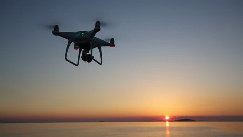 KAGAWA, JAPAN - May 18, 2017: Remote controlled drone Dji Phantom4Pro equipped with high resolution video camera flying above the sea against a sunset sky. 