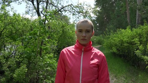 Early Morning Beautiful Girl in Pink Sweater is Jogging in the Woods in Early Spring,on a Background of Trees With Young Leaves,leads an Active Lifestyle