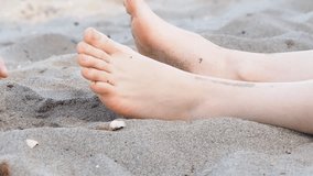Foot massage on a beach in sand, male and female Caucasian 