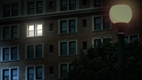 A typical New York style apartment or office building establishing shot at night with the lights from a window turning on. Simulated "day-for-night" composite.	 	