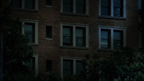 A typical New York style apartment or office building establishing shot at night with the lights from a window turning on then off. Simulated "day-for-night" composite.	 Day Matching ID: 10127561