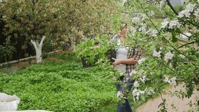 Slow motion video of beautiful young woman carrying seedling at backyard garden