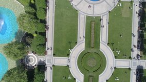 Aerial footage of a park with geometrical shapes, people and fountains.