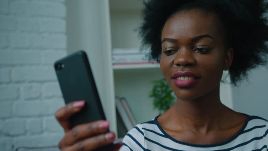 Black african american woman using smart phone at the office, at home. Surfing internet, reading news. Close up | Shutterstock HD Video #27170416