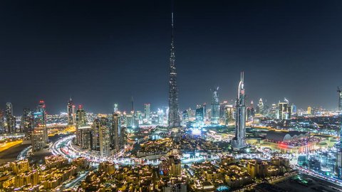 Dubai Downtown night timelapse with Burj Khalifa and other towers paniramic view from the top in Dubai, United Arab Emirates. Traffic on circle road and music fountain show