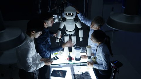 4K Electronics engineers collaborating on design of robot in dark lab Video Stok