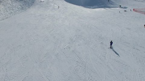 People ride on ski by mountain slope at sunny day. Aerial view