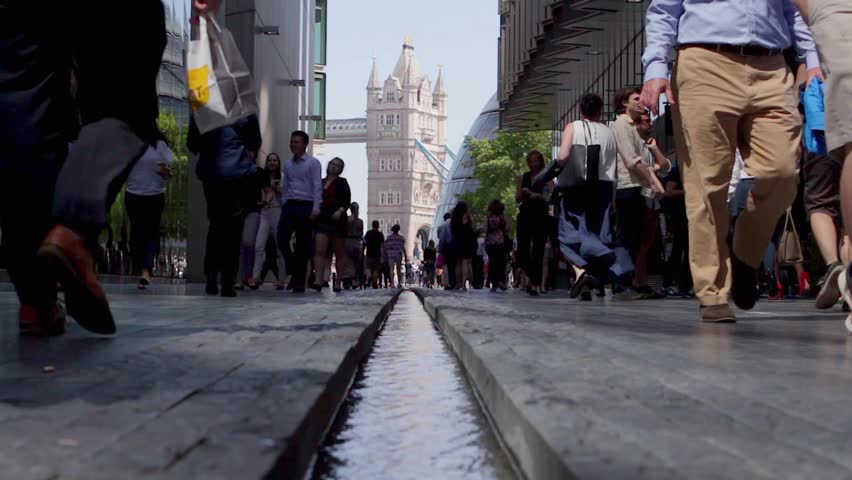 LONDON, UK - 25 MAY 2017:   Tourists and workers cross ‘the rill’ - a man made stream by Tower Bridge on a hot sunny day. Focus on foreground water.