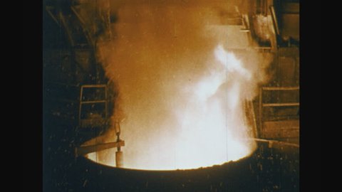 UNITED STATES: 1950s: rubbish in inferno inside processing plant. Water added to refuse in plant. Man controls machine